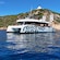 A catamaran anchored in calm waters near a hillside with a lighthouse in Ajaccio, Corsica